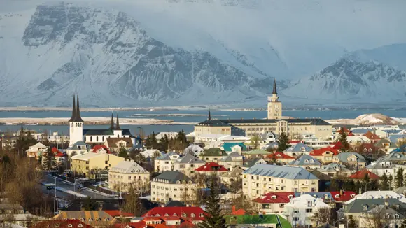 Aerial view of Reykjavík with snow-covered mountains in the background.